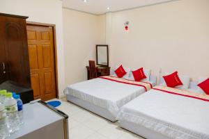 2 camas en una habitación de hotel con almohadas rojas en Kim Thuy Ngan Ha Hotel en Can Tho