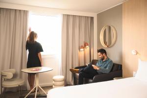 a man and a woman standing in a hotel room at Novotel Bordeaux Lac in Bordeaux