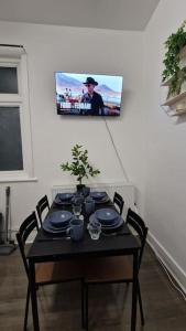 a black table with chairs and a tv on a wall at 2 Bed Apartment, Near Canary Wharf, O2, Excel, Airport in London