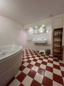 a bathroom with a tub and a checkered floor at De Skuorre in Baaiduinen