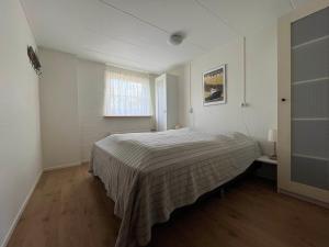 1 dormitorio con 1 cama en una habitación blanca en De Skuorre, en Baaiduinen
