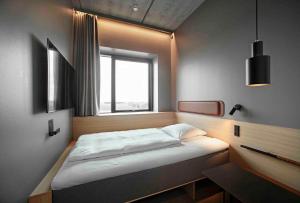 a small bedroom with a bed and a window at Zleep Hotel Horsens in Horsens