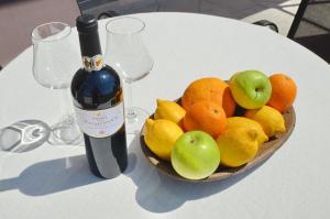 a bowl of fruit on a table with a bottle of wine at Porto Lastva Apartments in Tivat