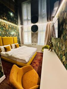 a bedroom with a bed and a yellow chair at Villa & Restaurant Levoslav House in Sibiu