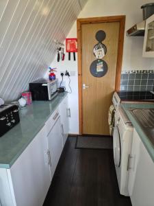 eine Küche mit weißen Schränken und einer Holztür in der Unterkunft SPECTAULAR SEA VIEWS! at Kingsdown Park, with Swimming pool No118 in Kingsdown