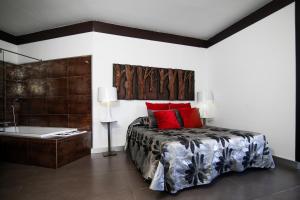 a bedroom with a bed with red pillows and a bath tub at Hotel ACG in Los Villares