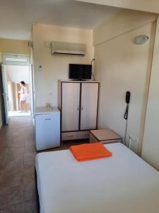 Un dormitorio con una cama blanca con una toalla naranja. en Arsuz Yunus Otel Bungalow, en Arsuz