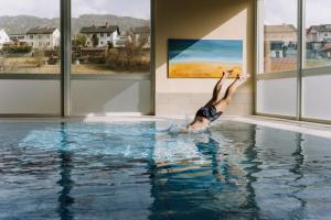 a woman diving into a swimming pool at Hotel Auszeit St Lambrecht in Sankt Lambrecht