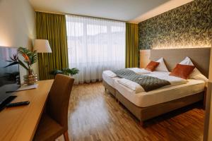 a hotel room with a bed and a desk and a desk at Hotel Auszeit St Lambrecht in Sankt Lambrecht