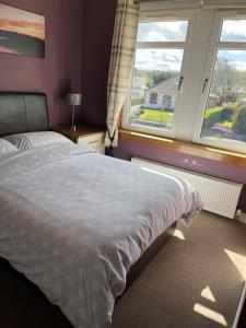 a bedroom with a bed and two windows at Hillhouse Blackhall in Edinburgh