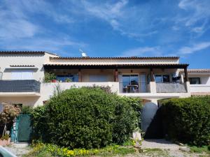a large white house with a balcony and bushes at Les Arbousiers in La Croix-Valmer