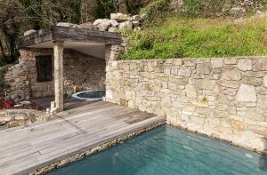 a swimming pool with a wooden deck next to a stone wall at Casa do Cebro Casa con piscina y jacuzzi privados in Santiago de Compostela +19 photos