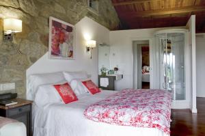 サンティアゴ・デ・コンポステーラにあるCasa do Cebro Casa con piscina y jacuzzi privadosのベッドルーム(赤い枕の大きな白いベッド付)