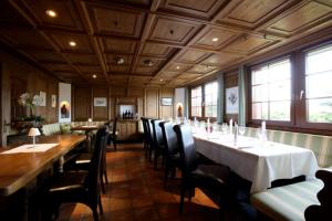 a dining room with tables and chairs and windows at Hotel Weinstube in Nendeln