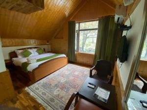 a bedroom with a bed and a desk and a television at The River Front Luxury Cottage By Stay Pattern in Anantnāg