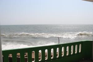 um banco verde junto ao oceano com ondas em Seagreen Beach resort em Pallipuram