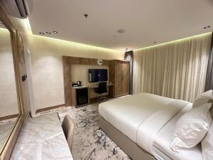 a bedroom with a large white bed and a desk at حياة تاون 3 in Umm Lajj