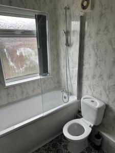 a bathroom with a toilet and a tub and a window at Room in Manchester in Manchester