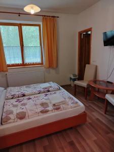 a bedroom with a bed and a table and window at Akácliget Vendégház és Major in Ófehértó