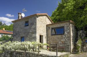 una casa de piedra con un banco delante en Casa de Afora Casa con piscina y jacuzzi privados en Santiago de Compostela