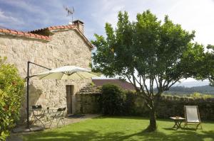 un jardín con sombrilla, mesa y árbol en Casa de Afora Casa con piscina y jacuzzi privados, en Santiago de Compostela