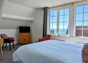a bedroom with a bed and a tv and windows at The Westcott by the Sea - Just for Adults in Falmouth