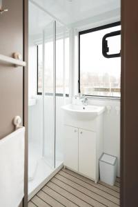 baño blanco con lavabo y ventana en Hausboot-Tortuga, en Dömitz