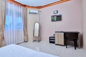 una camera con letto, scrivania e specchio di PB & J Guest House Entebbe a Entebbe