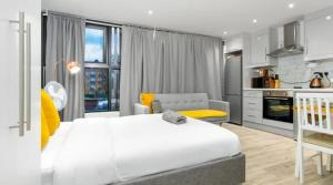 a bedroom with a large white bed and a kitchen at City Studio - 3 Sleeps in London