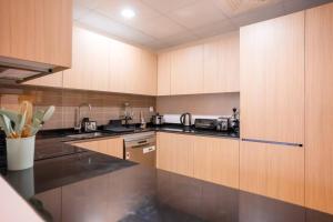 een keuken met houten kasten en zwarte aanrechtbladen bij Zapbed Villa C62-03 in Dubai