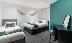 um quarto com 2 camas, uma secretária e um espelho. em Hackins Hey spacious Liverpool stays central city em Liverpool