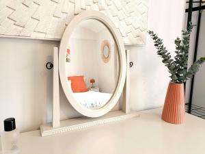 - un miroir rond dans une pièce blanche avec un vase dans l'établissement Charming Terrace Home in Whitchurch, à Whitchurch