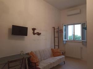 a living room with a couch and a tv on the wall at B&B La casa degli artisti in Ostuni