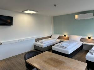 Cette chambre comprend 2 lits et une table. dans l'établissement Hive Apartments - direkt an der Hannover Messe, à Hanovre