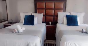 two beds with blue pillows in a hotel room at Kgakgamela road lodge in Driekop