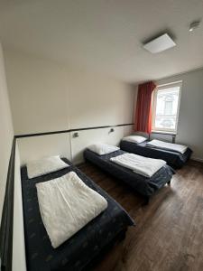 a room with three beds and a window at Central Hotel in Offenbach