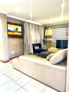 a living room with a couch and a tv on a wall at 3 Bedroom in Secure Estate Loadshedding free in Midrand