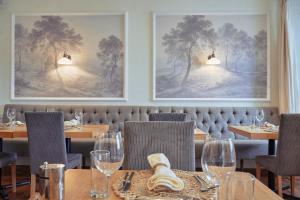Wilding Hotel في Brough: مطعم على الحائط طاولات وكراسي ولوحات