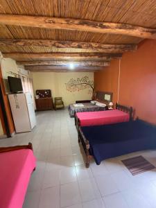 a large room with two beds and a refrigerator at Munay EcoHostal - Cabañas de Adobe in Tinogasta