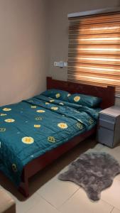 a bed with a blue comforter with yellow eggs on it at Oyibi Saasabi Apartment in Oyibi