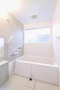 ein weißes Bad mit einer Badewanne und einem Fenster in der Unterkunft Mitao bld - Huge 3 bedroom Apt 4mins walk PeacePark 6ppl in Hiroshima