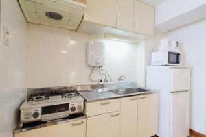 a white kitchen with a stove and a refrigerator at Mitao bld - 2 Bedroom Apt 4mins to PeacePark for 9ppl in Hiroshima