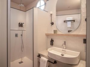 a white bathroom with a sink and a mirror at Hotel Louison in Paris