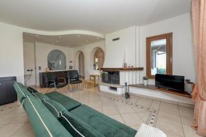 een woonkamer met een groene bank en een televisie bij Villa Oleander in Manerba del Garda