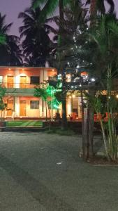 dom z palmami przed nim w nocy w obiekcie Suvarna Shree Resort w mieście Diveagar