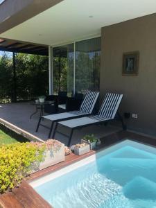 um pátio com 2 cadeiras e uma piscina em Casa en Vistalba para dos personas con yacuzzi de temporada en la terraza em Luján de Cuyo