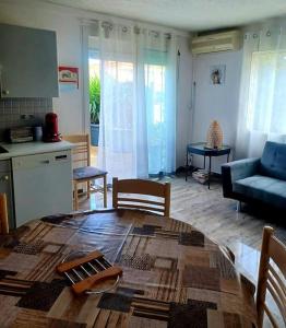 uma cozinha e sala de estar com uma mesa e uma sala de estar em Appartement 2 chambres, avec terrasse/parking em Palavas-les-Flots