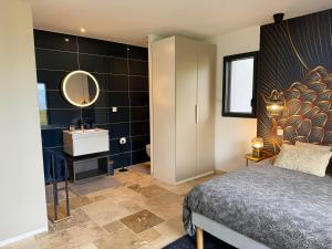 a bedroom with a bed and a bathroom with a sink at Les Hutins in Gex