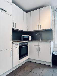 a kitchen with white cabinets and a sink and a microwave at FeWo Euregio II - mit Terrasse in Nordhorn