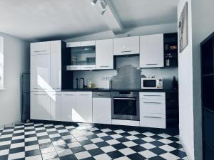 a kitchen with white cabinets and a checkered floor at FeWo Lindenallee II in Nordhorn
